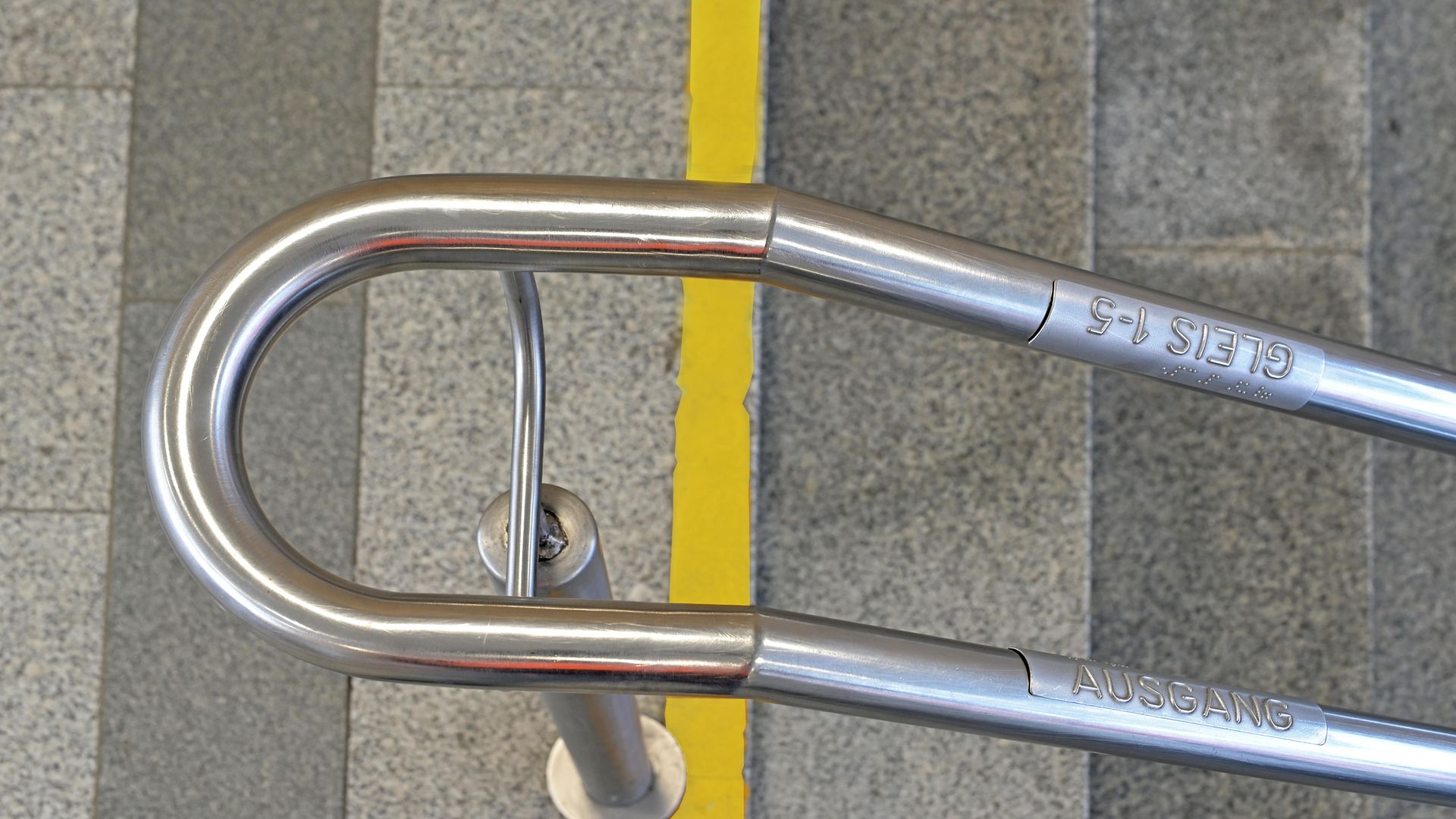 Taktiles Handlaufschild an einer Treppe mit Hinweis zu Gleis und Ausgang