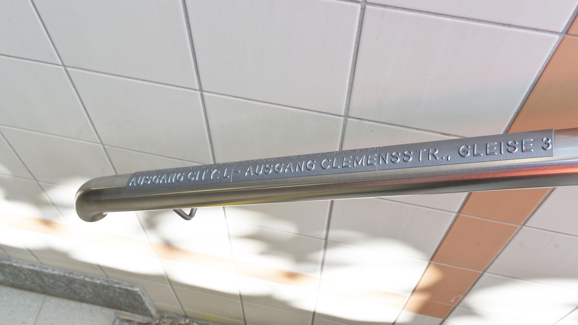 Taktiles Handlaufschild an einer Treppe mit Hinweis zu den Ausgängen