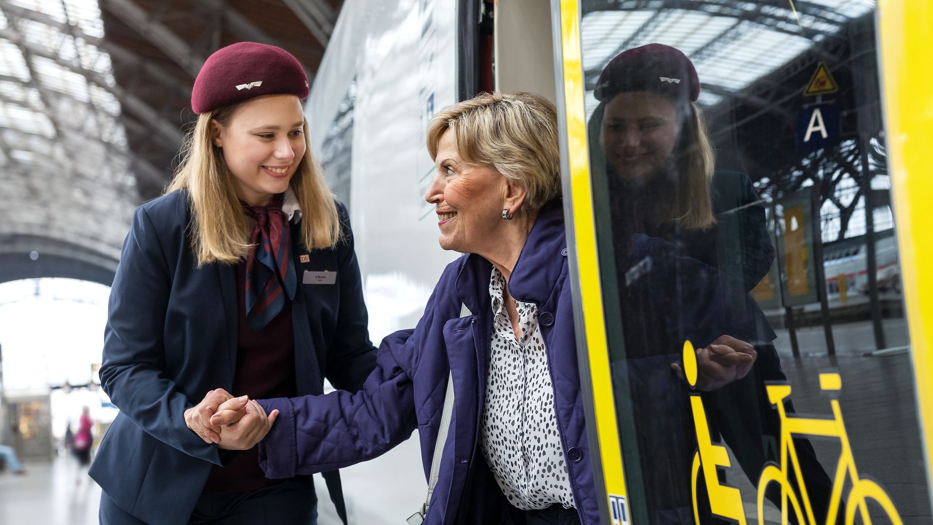 Eine Servicemitarbeiterin unterstützt eine Reisende beim Ausstieg aus dem Zug