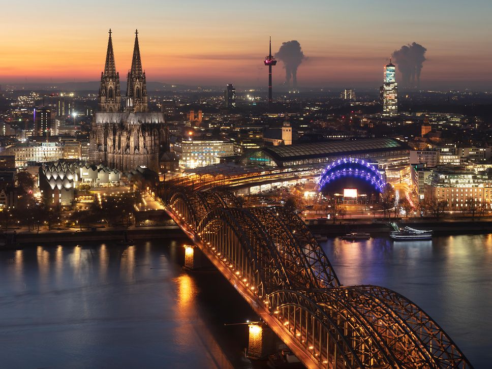 Blick auf die Stadtsilhouette von Köln mit Hauptbahnhof bei Nacht