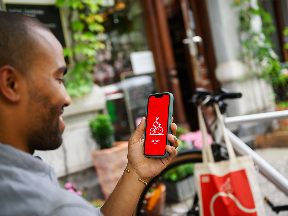 Ein Radfahrer nutzt mit dem Smartphone die App DB Rad+