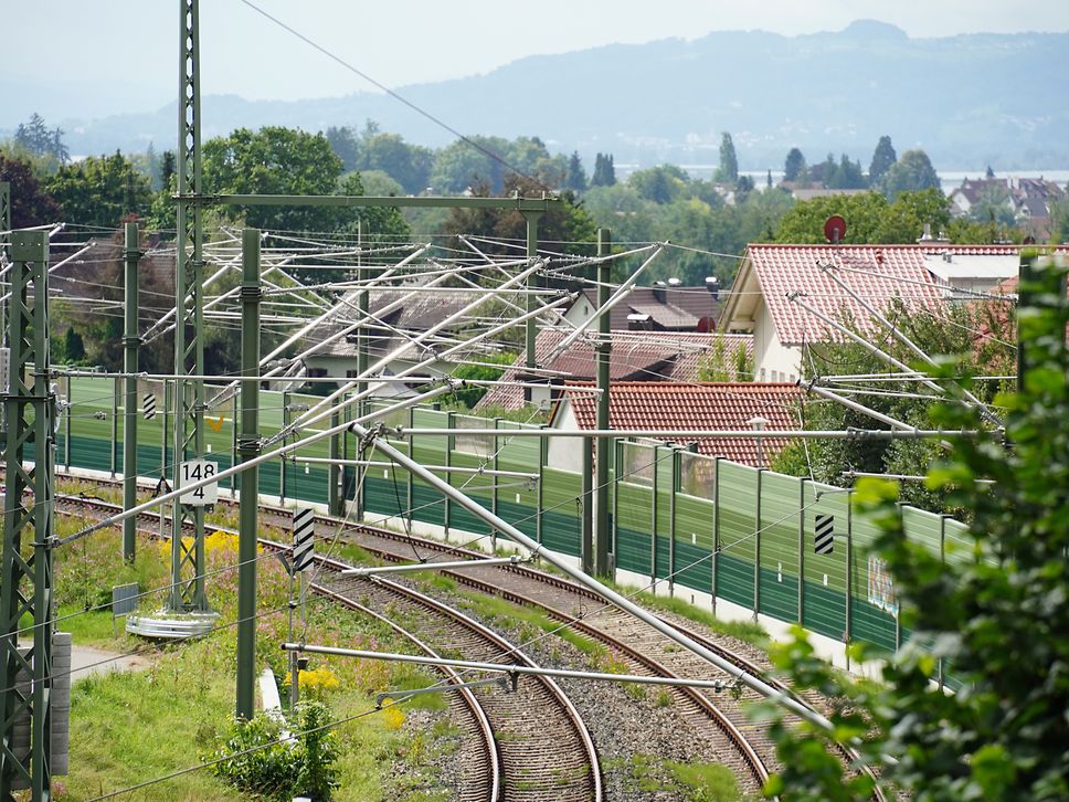 Lärmschutzwände an einer Bahnstrecke, im Hintergrund Wohnhäuser