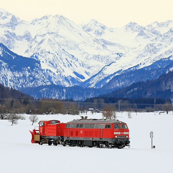 Die Bahn unterwegs im Freistaat Bayern in der Winterzeit. Eine Lok der Baureihe 218 überführt einen Schneepflug.