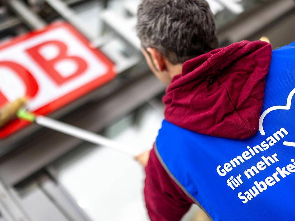 Ein Mann säubert das DB-Logo am Empfangsgebäude