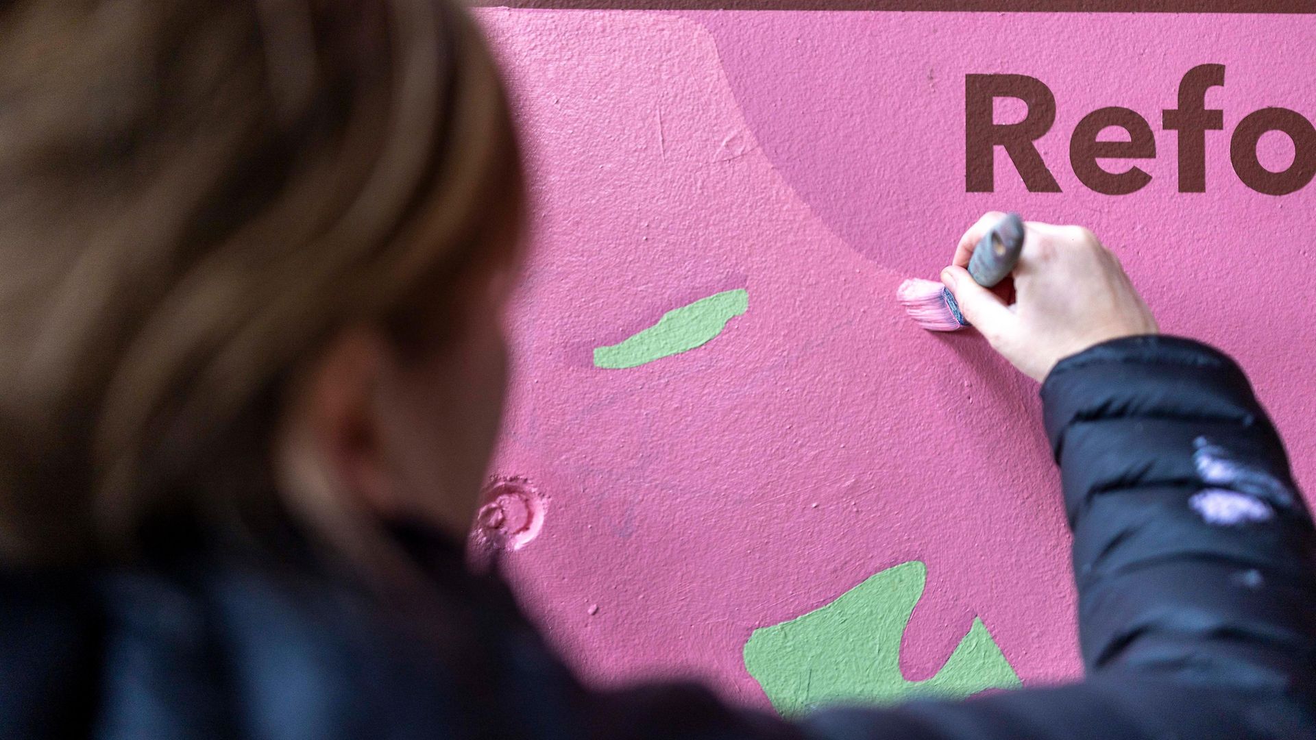 Eine Frau streicht frische Farbe an die Wand