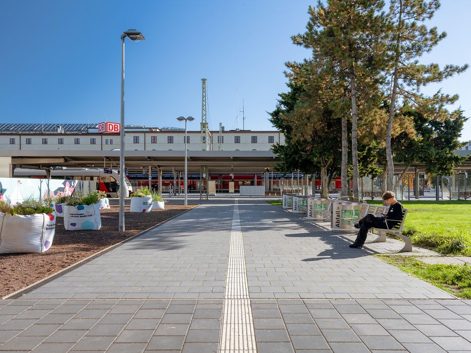 Blick auf Grünanlagen, Sitzgelegenheiten und Bahnsteige des Magdeburger Hauptbahnhofs